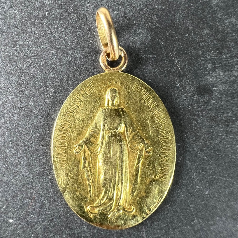 An oval 18k yellow gold pendant depicting the Virgin Mary with French devotional text embossed along the border. View II