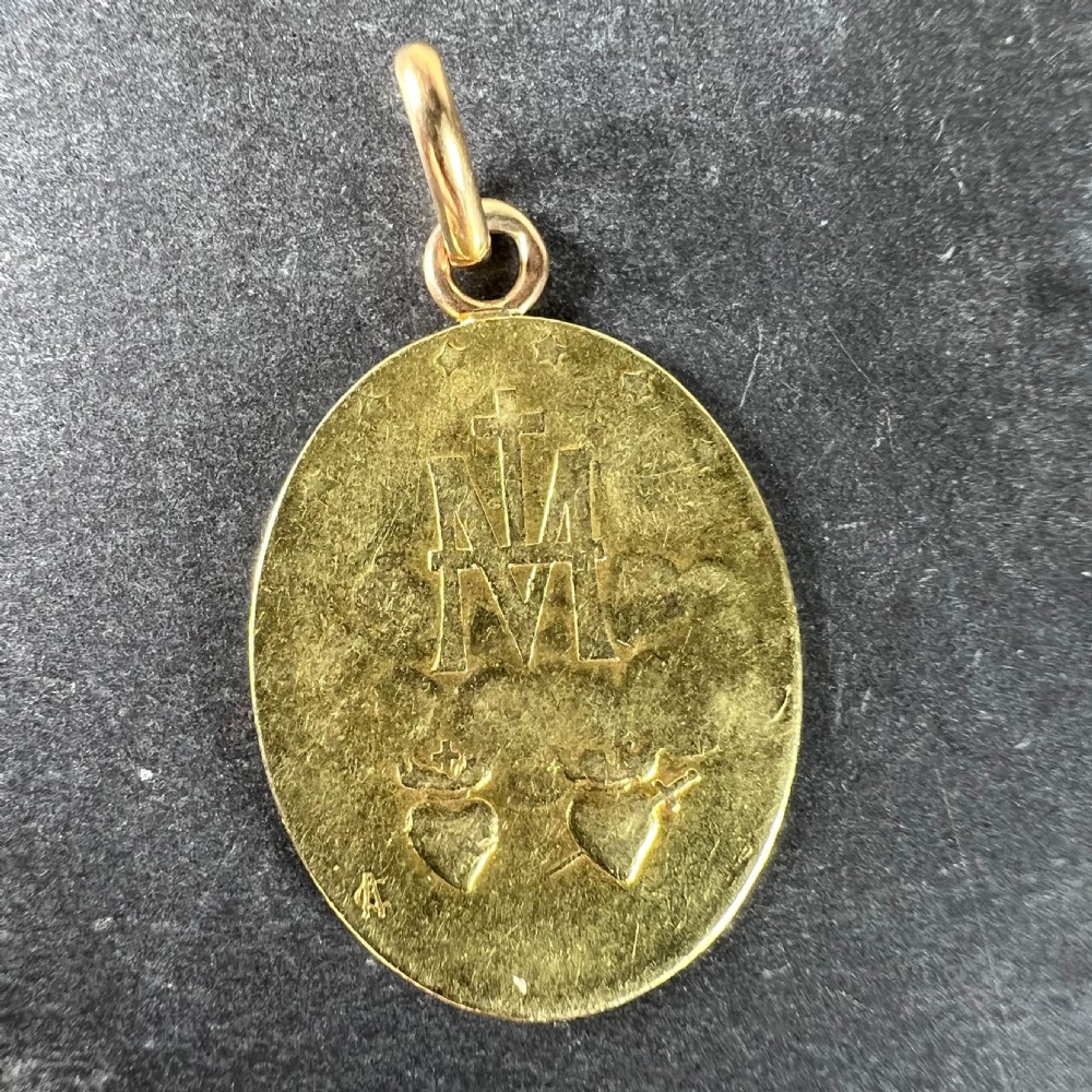 An oval 18k yellow gold pendant depicting the Virgin Mary with French devotional text embossed along the border. View III