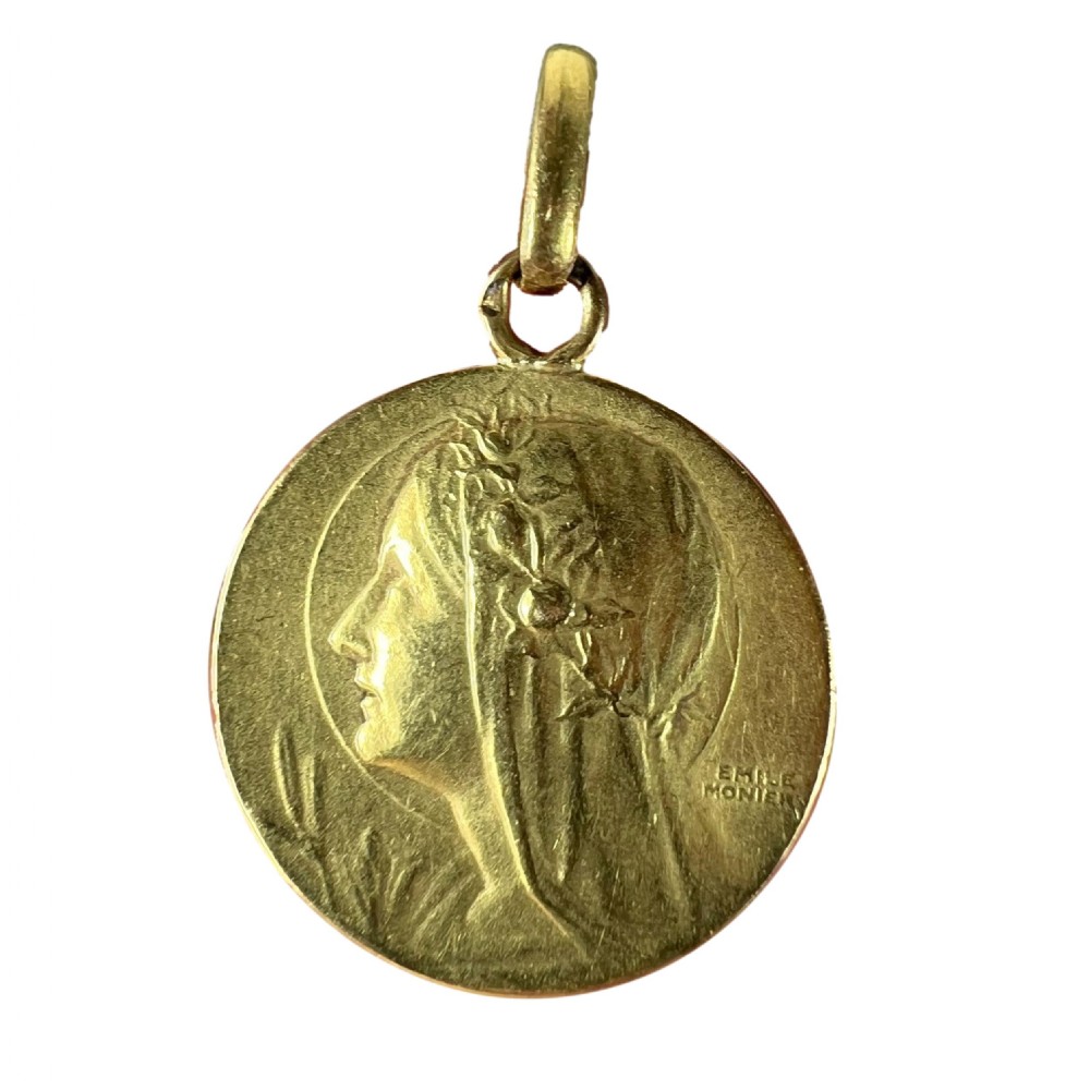 A circular 18k yellow gold pendant featuring a relief profile portrait of the Virgin Mary signed by Emile Monier.