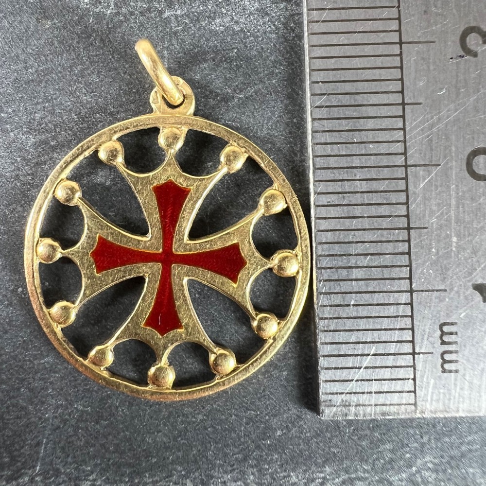 A circular 18ct yellow gold pendant featuring a central red enamelled cross surrounded by an openwork rim with small spherical accents. View X