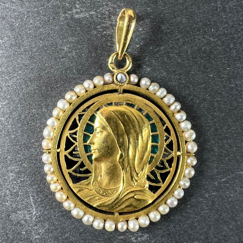 An 18k gold circular pendant featuring a sculpted profile of the Virgin Mary surrounded by translucent blue and green plique-a-jour enamel and framed by seed pearls. View V
