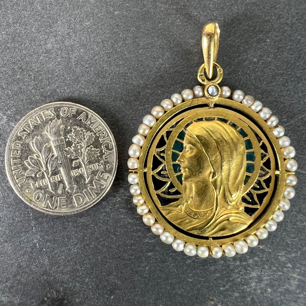 An 18k gold circular pendant featuring a sculpted profile of the Virgin Mary surrounded by translucent blue and green plique-a-jour enamel and framed by seed pearls. View XV