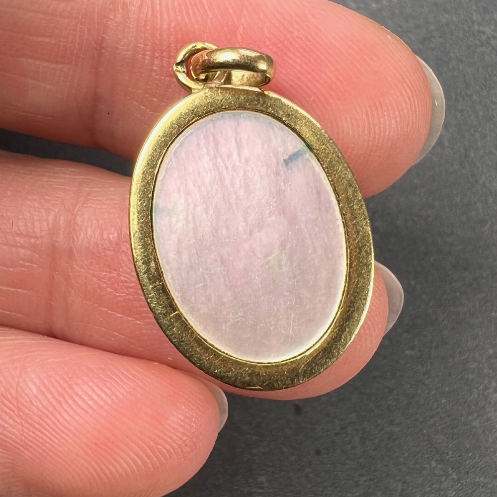 An oval 18-carat yellow gold pendant featuring a carved mother-of-pearl profile of the Virgin Mary encircled by a royal blue enamelled border with gold stars. View VII