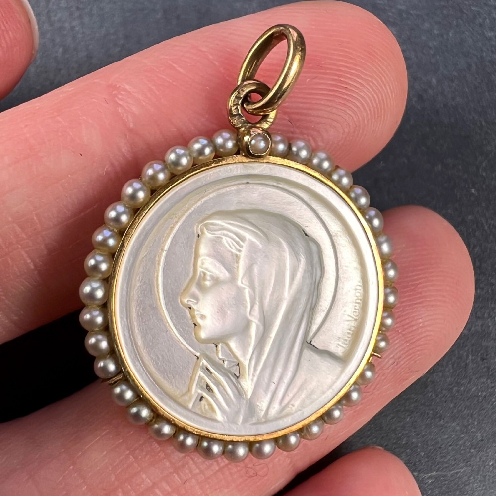 A circular gold pendant featuring a carved mother of pearl profile of the Virgin Mary encircled by seed pearls. View V