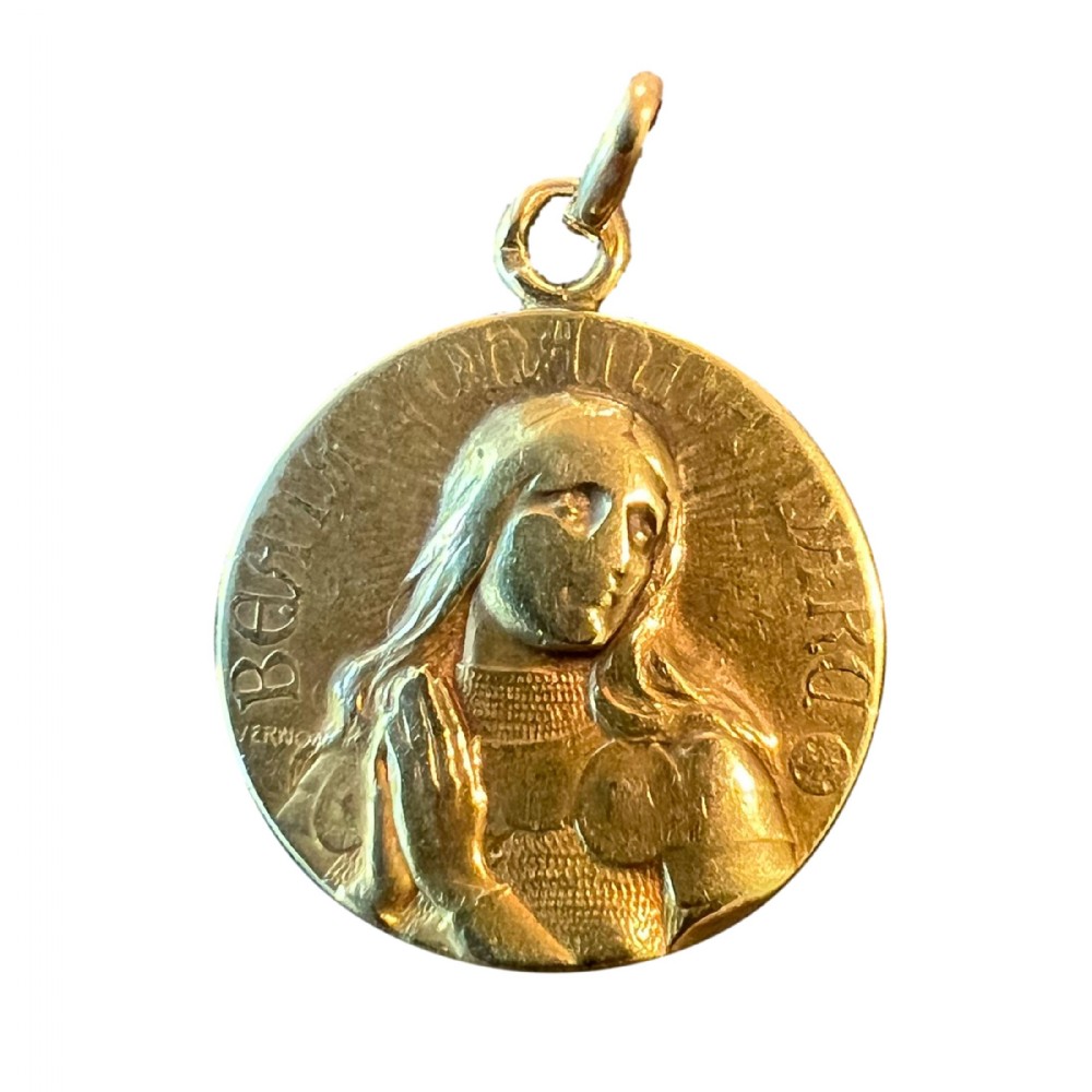 A circular 18K yellow gold devotional medal featuring a relief profile portrait of Saint Joan of Arc.