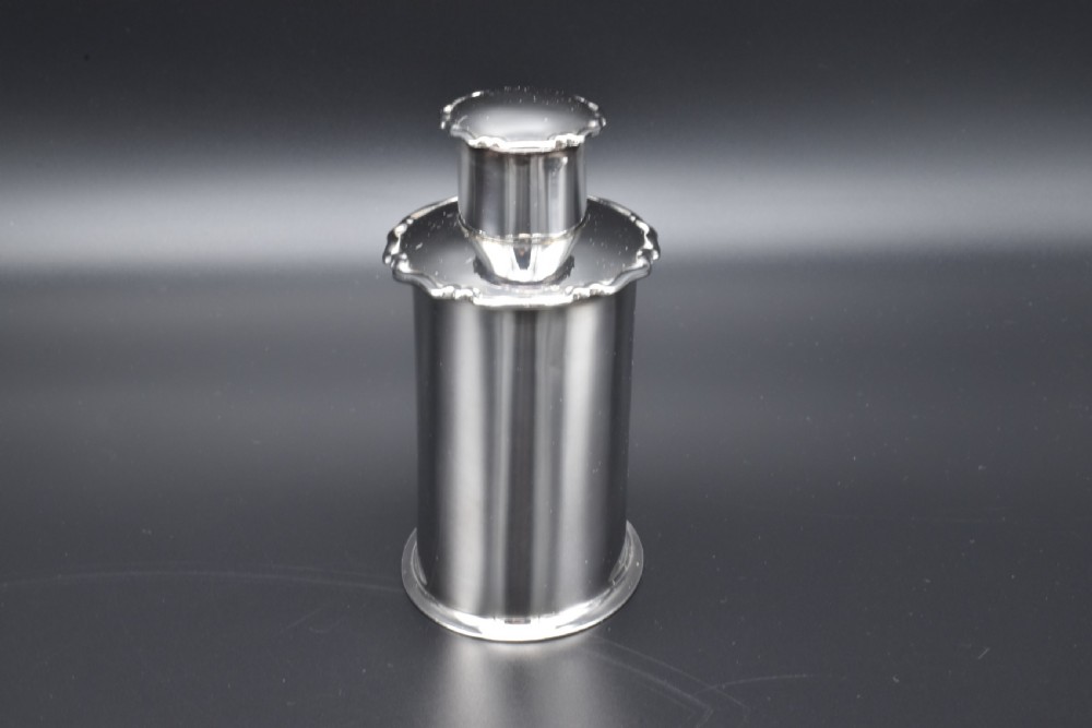 A cylindrical Edwardian sterling silver tea caddy with a scalloped edge lid and an engraved monogram on the front. View IV
