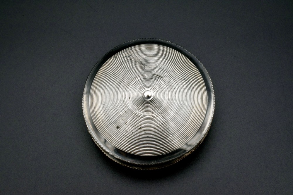 A circular 19th-century Dutch sterling silver snuff box featuring concentric engine-turned engraving and reeded borders. View III