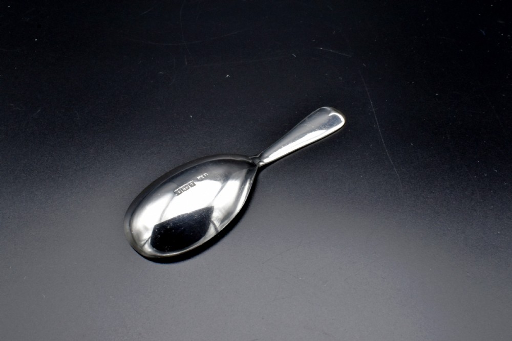 A sterling silver caddy spoon featuring a broad oval scoop bowl and a short flat handle with horizontal line accents. View II