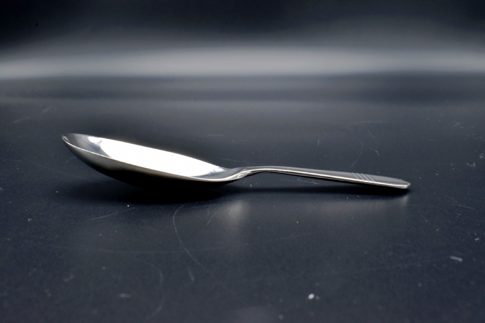 A sterling silver caddy spoon featuring a broad oval scoop bowl and a short flat handle with horizontal line accents. View VI