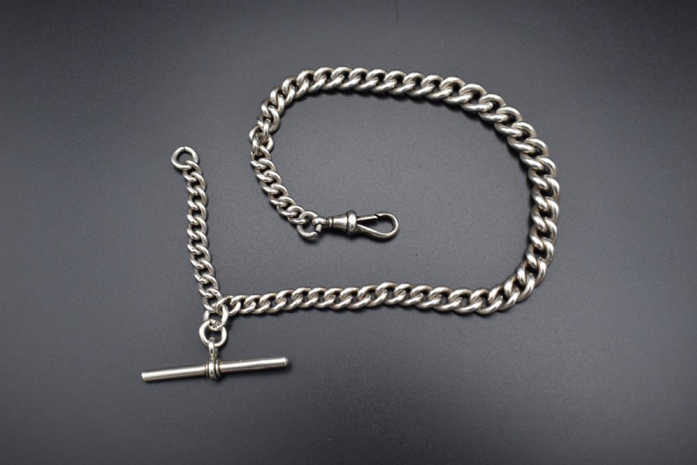 A Victorian sterling silver Albert watch chain featuring heavy curb links, a T-bar fastener, and a swivel clasp.
