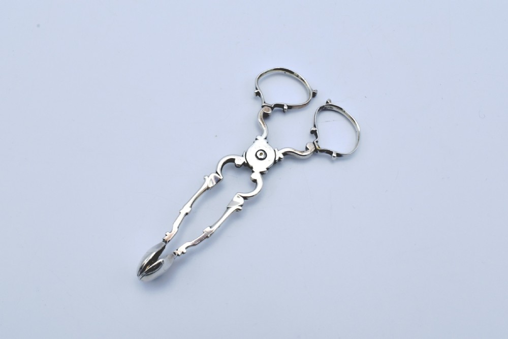 An 18th-century Georgian sterling silver scissor-form sugar nip with curved scroll handles and shell-shaped grips.