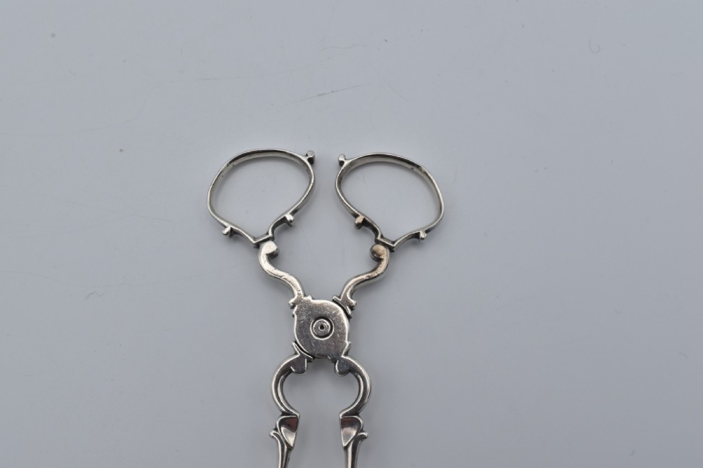 An 18th-century Georgian sterling silver scissor-form sugar nip with curved scroll handles and shell-shaped grips. View III