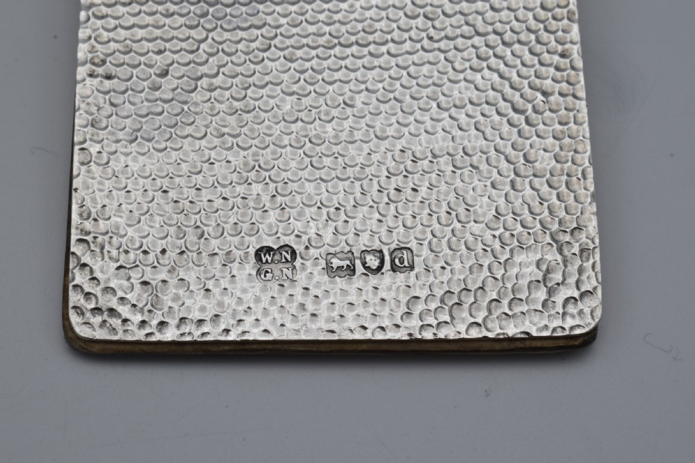 A Victorian sterling silver pocket notebook featuring a hammered finish, central monogram cartouche, top suspensory ring, and British hallmarks dated 1899. View III