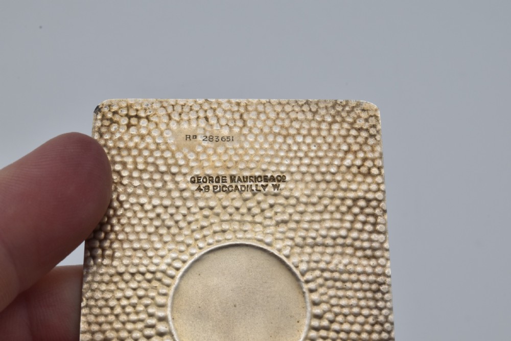 A Victorian sterling silver pocket notebook featuring a hammered finish, central monogram cartouche, top suspensory ring, and British hallmarks dated 1899. View VIII