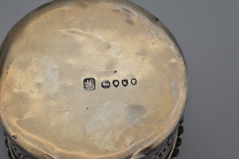 A circular Victorian sterling silver snuff box with repousse floral scrollwork on the lid and fluted sides. View VI