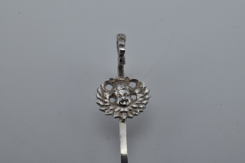 Victorian sterling silver caddy spoon featuring an embossed figurative scene in the scalloped bowl and a cherub mask terminal. View III