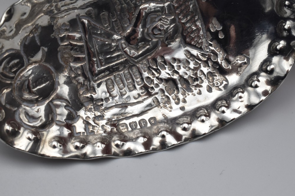 Victorian sterling silver caddy spoon featuring an embossed figurative scene in the scalloped bowl and a cherub mask terminal. View IV