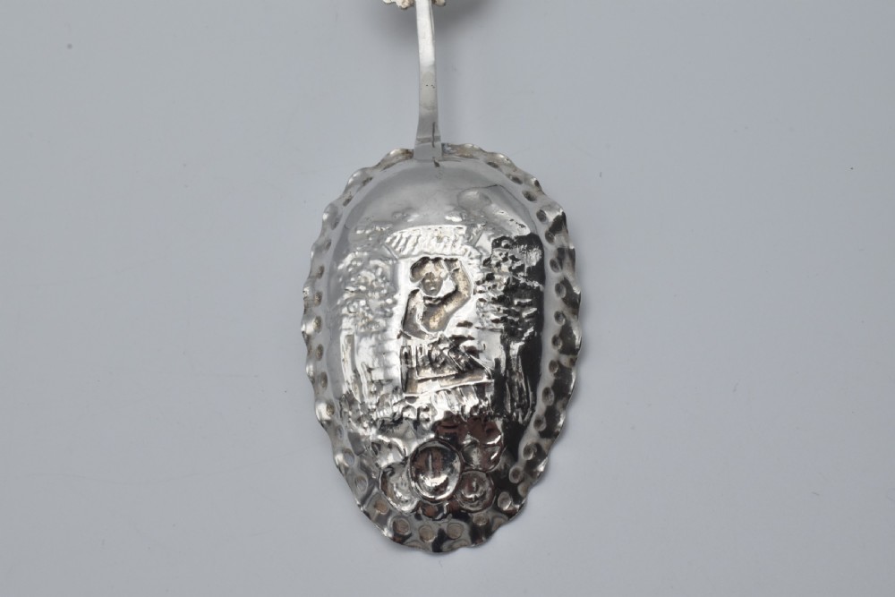 Victorian sterling silver caddy spoon featuring an embossed figurative scene in the scalloped bowl and a cherub mask terminal. View VII