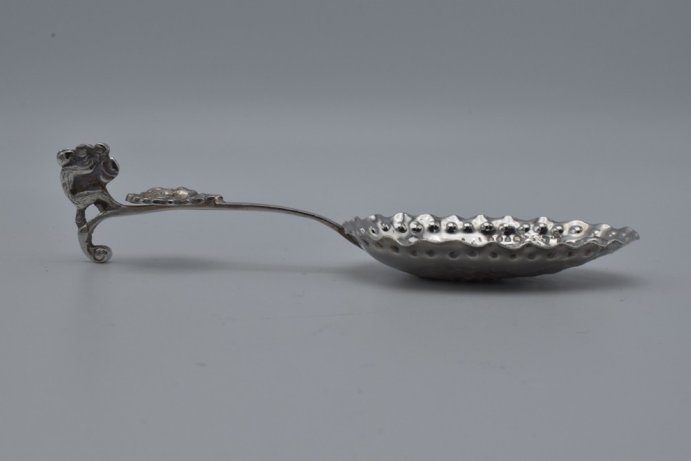 Victorian sterling silver caddy spoon featuring an embossed figurative scene in the scalloped bowl and a cherub mask terminal. View VIII