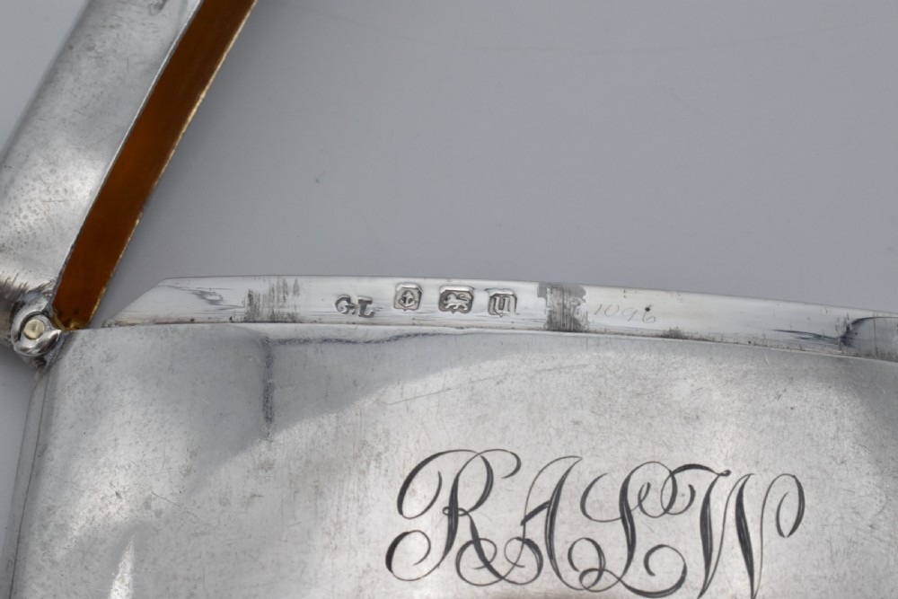 A curved sterling silver card case with hand-engraved monogram initials and visible British hallmarks near the top hinge. View IV