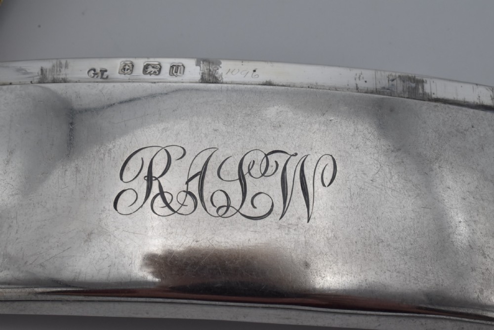A curved sterling silver card case with hand-engraved monogram initials and visible British hallmarks near the top hinge. View V