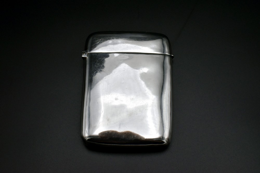 A polished Victorian sterling silver pocket card case with a hinged lid displayed on a dark background.