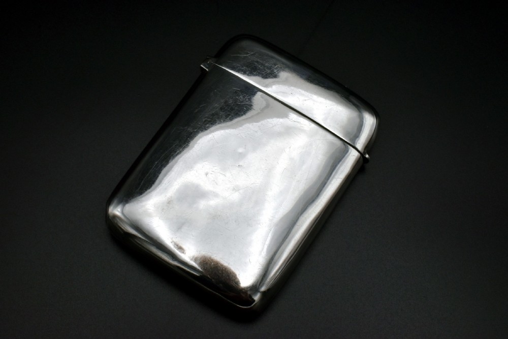 A polished Victorian sterling silver pocket card case with a hinged lid displayed on a dark background. View II