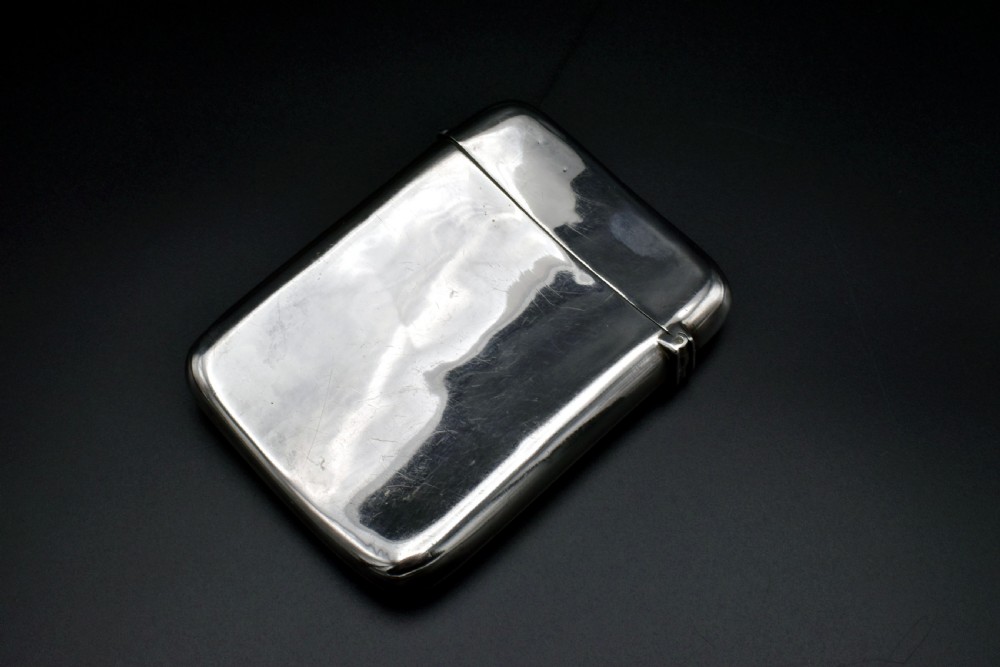 A polished Victorian sterling silver pocket card case with a hinged lid displayed on a dark background. View III