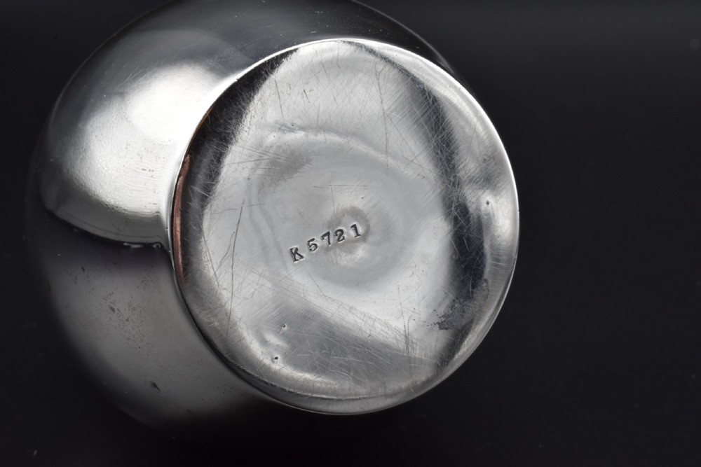 A small, bulbous sterling silver miniature tea caddy with a fitted lid, round ball finial, and visible British hallmarks stamped around the neck. View VII