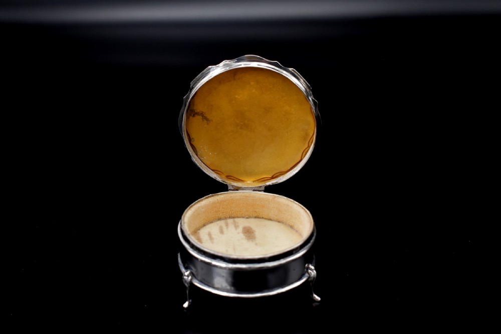 A circular sterling silver dressing table box with a shaped rim and cabriole feet displayed on a dark surface. View VI