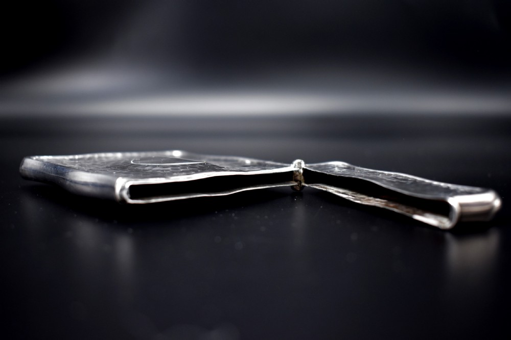 A hinged Edwardian sterling silver card case featuring a spot-hammered textured surface and a smooth circular central cartouche. View V