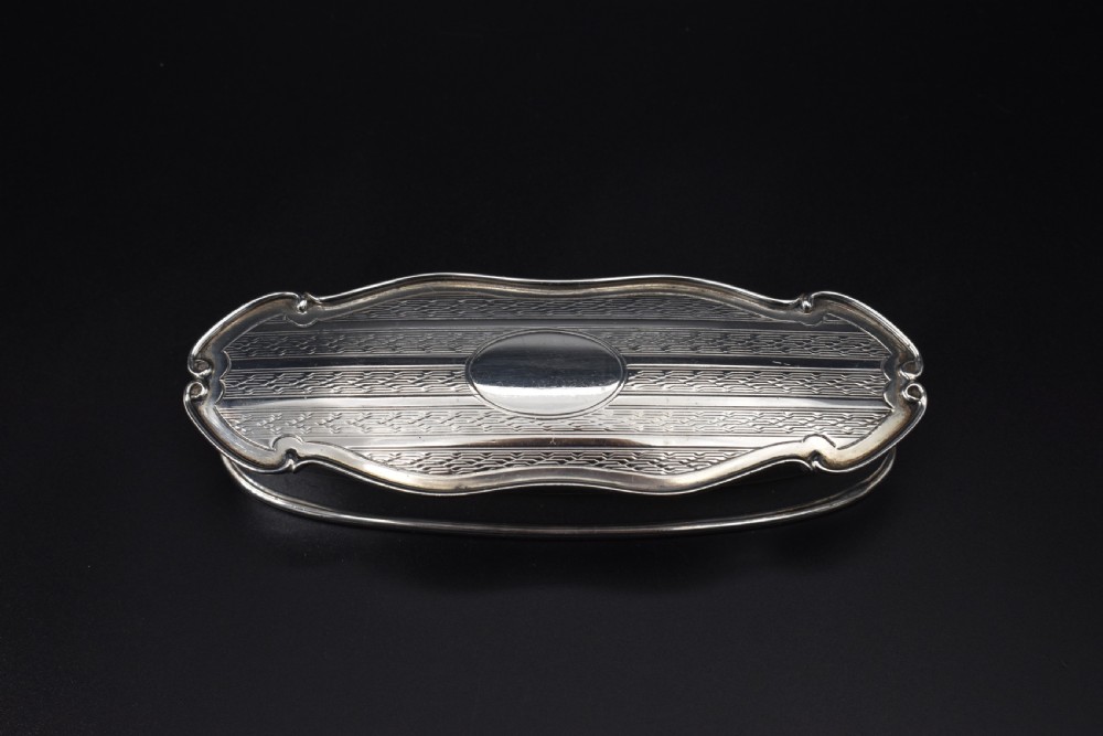 An elongated, oval Edwardian sterling silver powder box featuring engine-turned engraving on the lid and an unengraved central cartouche. View II