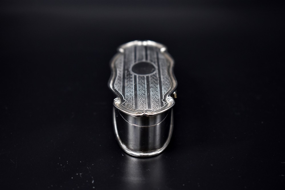 An elongated, oval Edwardian sterling silver powder box featuring engine-turned engraving on the lid and an unengraved central cartouche. View IV