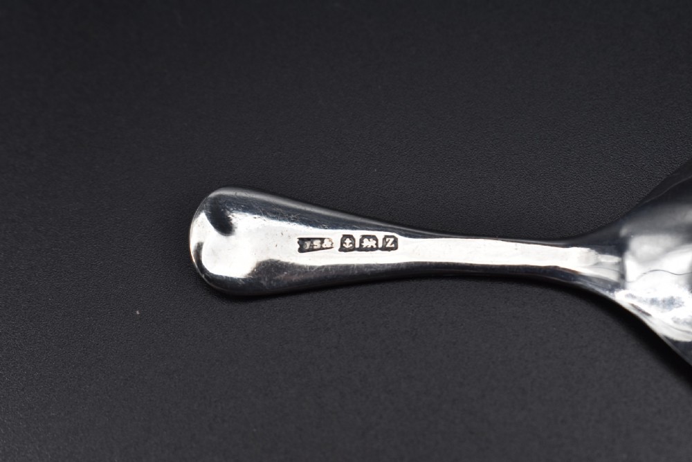 A late Victorian sterling silver caddy spoon featuring a plain oval bowl and a short flared handle against a dark background. View III