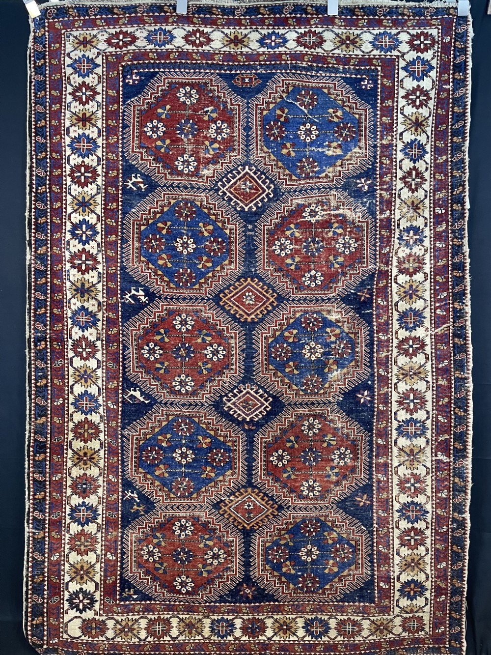 An antique hand-knotted Caucasian Surakhani wool rug featuring geometric octagonal medallions in deep blue and terracotta red on an indigo field with layered decorative borders.