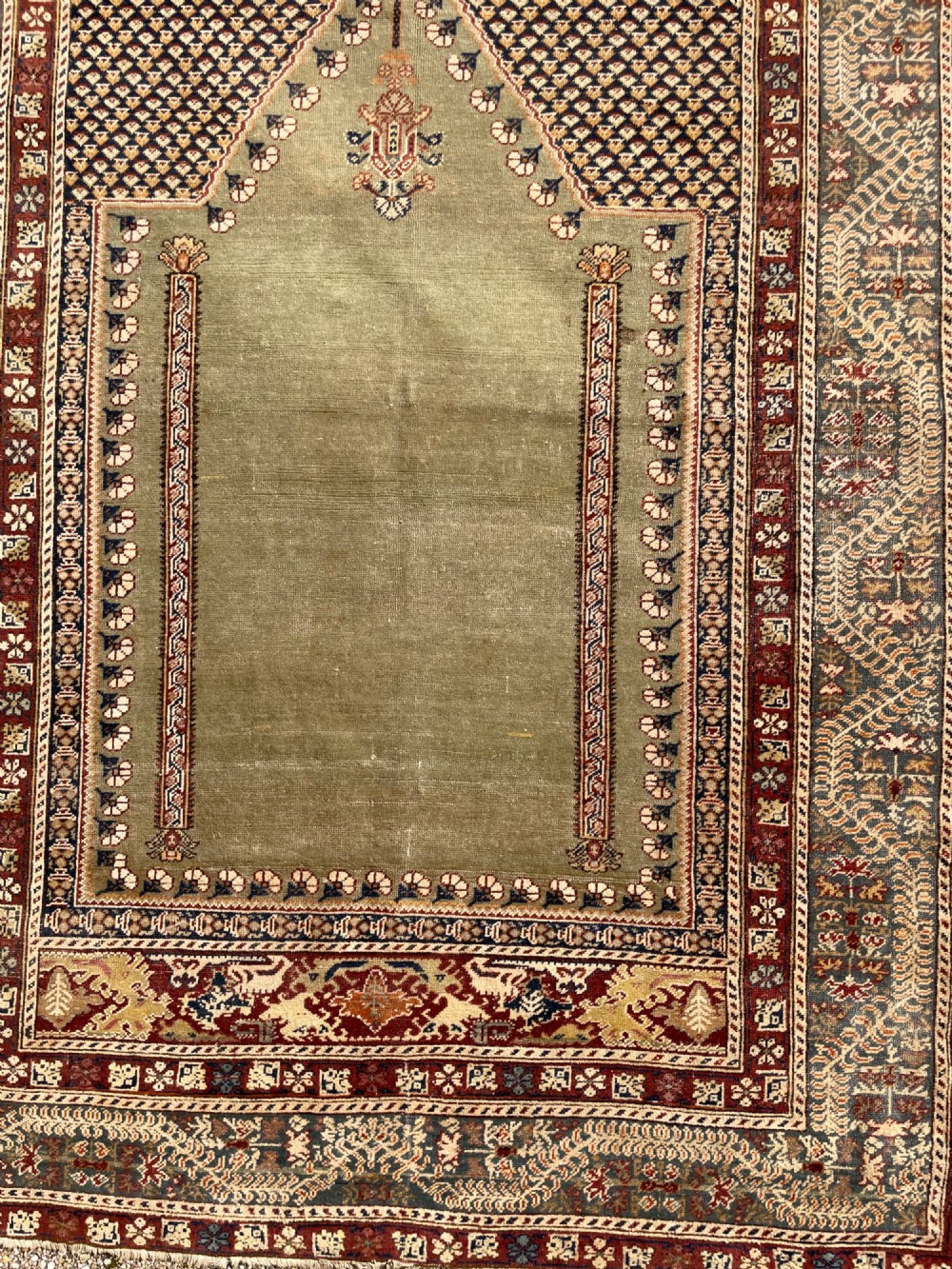 An antique hand-knotted Anatolian Ghiordes prayer rug featuring a central sage green arched niche enclosed by detailed rust red and blue decorative borders. View XI