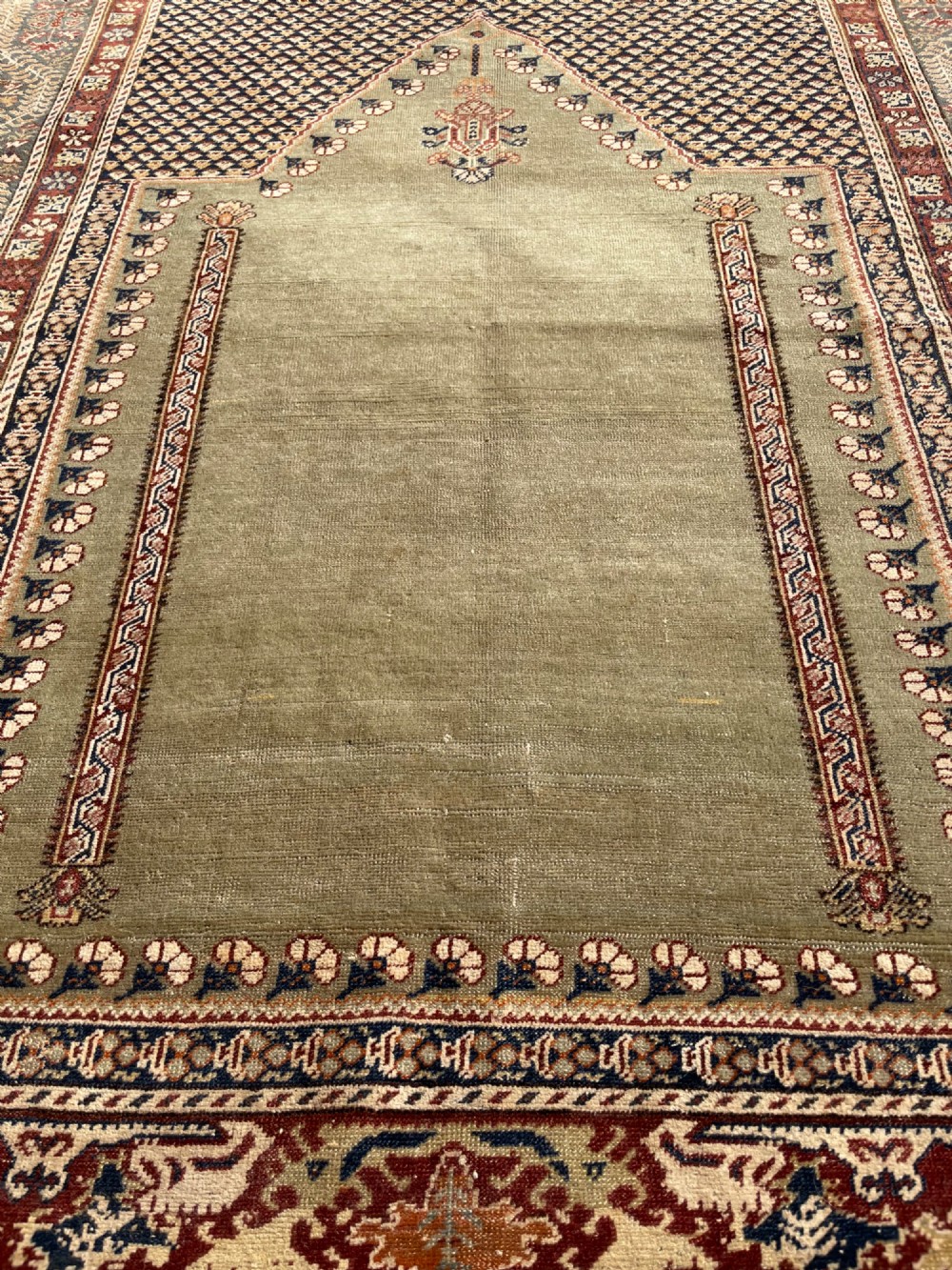 An antique hand-knotted Anatolian Ghiordes prayer rug featuring a central sage green arched niche enclosed by detailed rust red and blue decorative borders. View XIII
