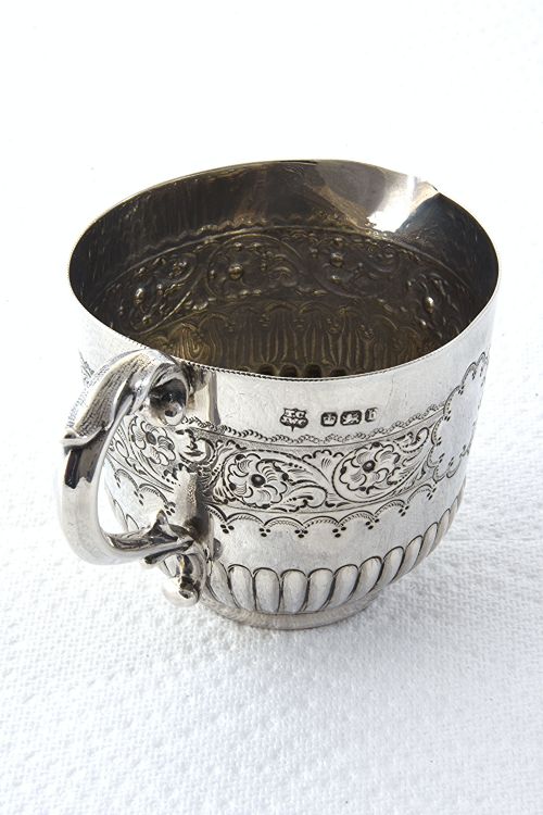 fig 1. A late Victorian sterling silver cream jug featuring detailed floral scroll chasing along the upper body, lower fluted gadrooning, and a curved handle.