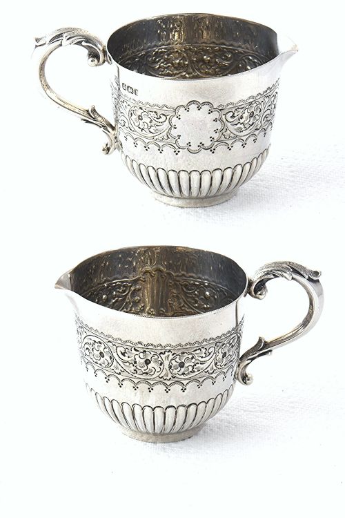 fig 3. A late Victorian sterling silver cream jug featuring detailed floral scroll chasing along the upper body, lower fluted gadrooning, and a curved handle.
