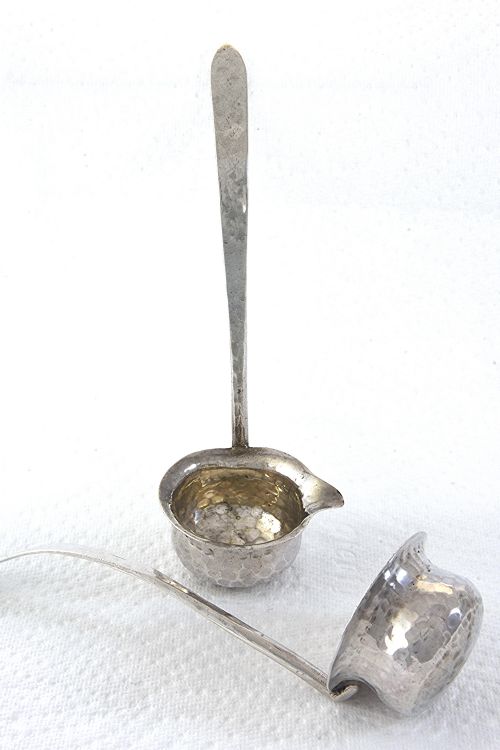 fig 1. A pair of hand-hammered silver toddy ladles featuring spouted bowls and long, flattened handles.
