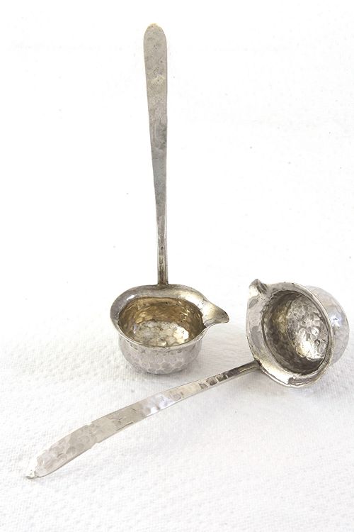 fig 2. A pair of hand-hammered silver toddy ladles featuring spouted bowls and long, flattened handles.