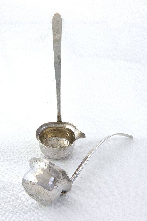 fig 3. A pair of hand-hammered silver toddy ladles featuring spouted bowls and long, flattened handles.