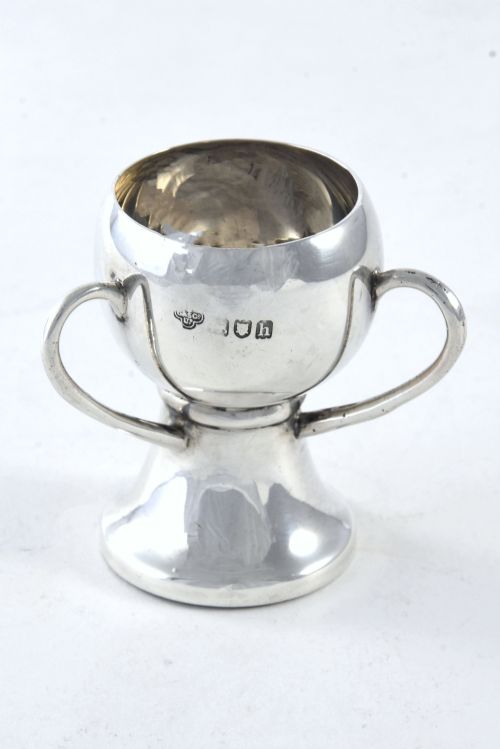 fig 1. An Edwardian sterling silver twin-handled trophy cup featuring a flared pedestal base and an engraved heraldic crest of a unicorn on the central bowl.