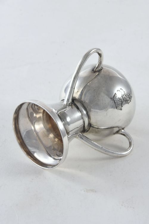 fig 3. An Edwardian sterling silver twin-handled trophy cup featuring a flared pedestal base and an engraved heraldic crest of a unicorn on the central bowl.