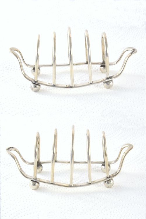fig 2. A 1939 sterling silver four-slice toast rack featuring curved wire arches, raised ball feet, and visible hallmarking.