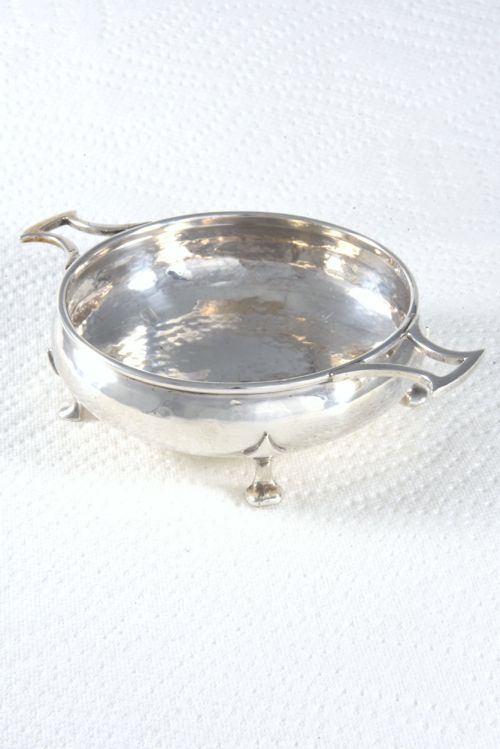 fig 1. A small round George V sterling silver trinket dish featuring twin side handles, planished surface texture, and three small feet.