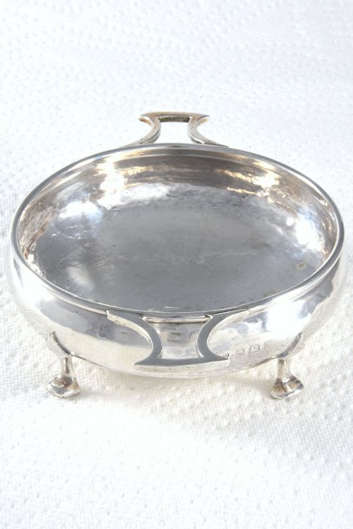 fig 2. A small round George V sterling silver trinket dish featuring twin side handles, planished surface texture, and three small feet.
