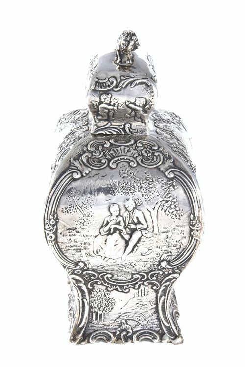 fig 2. A Victorian sterling silver tea caddy featuring a shaped bombe body with detailed repousse pastoral scenes and a lion finial on the lid.