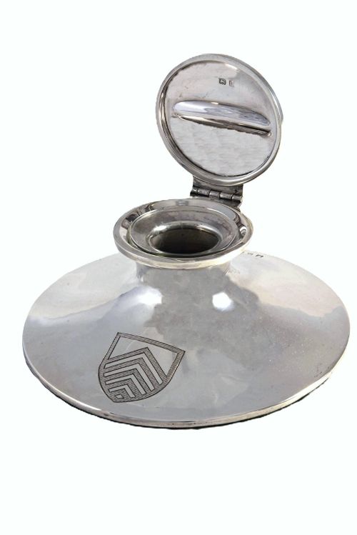 fig 1. A polished sterling silver capstan-shaped inkwell featuring a wide sloped base and an engraved crest motif.