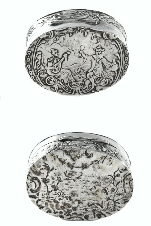 fig 1. An oval sterling silver Edwardian snuff box with a relief scene on the hinged lid and floral scrollwork around the sides.